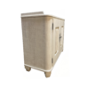 Cream-colored freestanding wooden cabinet with two paneled doors and black handles on short feet, used for storage.