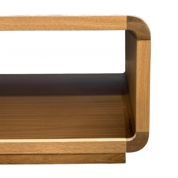 Partial view of a two-tier wooden shelf or stand with rounded corners and open back, showing warm oak finish.