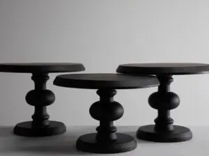 Close-up of black wooden chess pieces on a white tabletop against a plain gray wall.
